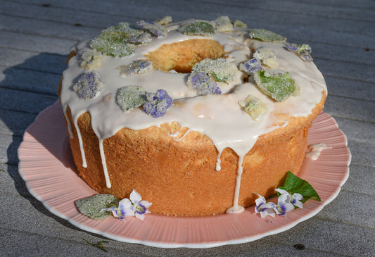 round pound cake topped with white glaze and candied violets