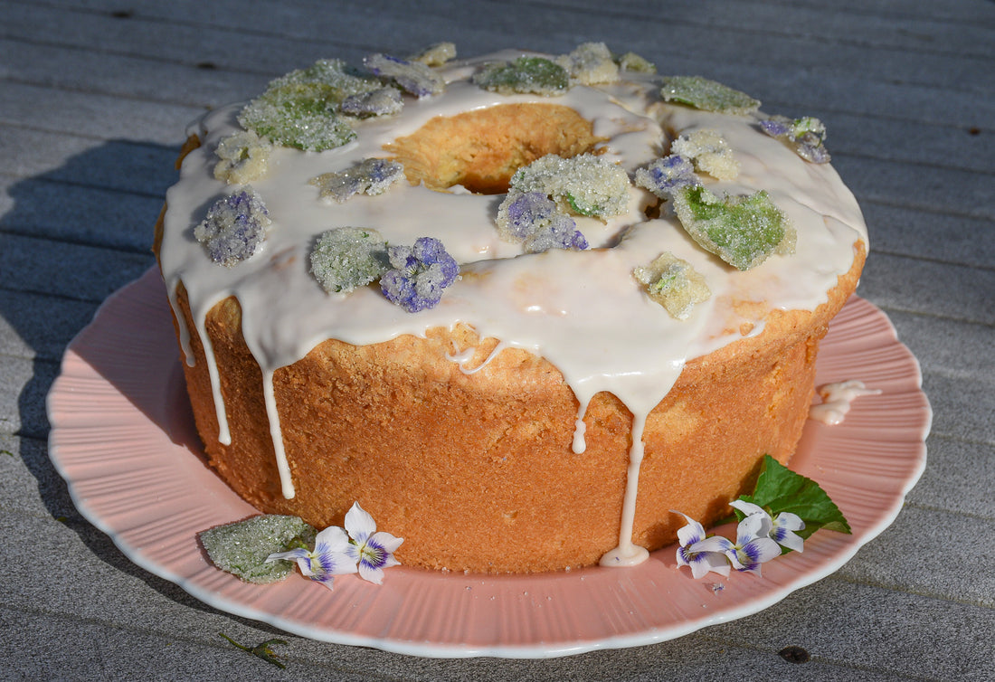 round pound cake topped with white glaze and candied violets